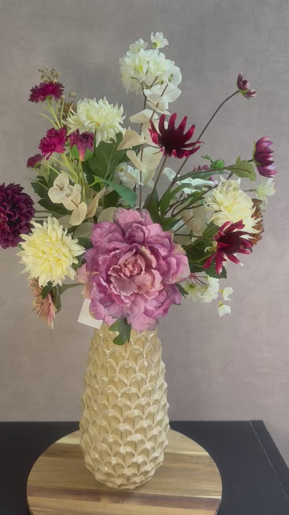 Video van Kunstboeket Noëlle – volle bos kunstbloemen in beige, bruin en bordeaux tinten in een beige vaas tegen grijze achtergrond.