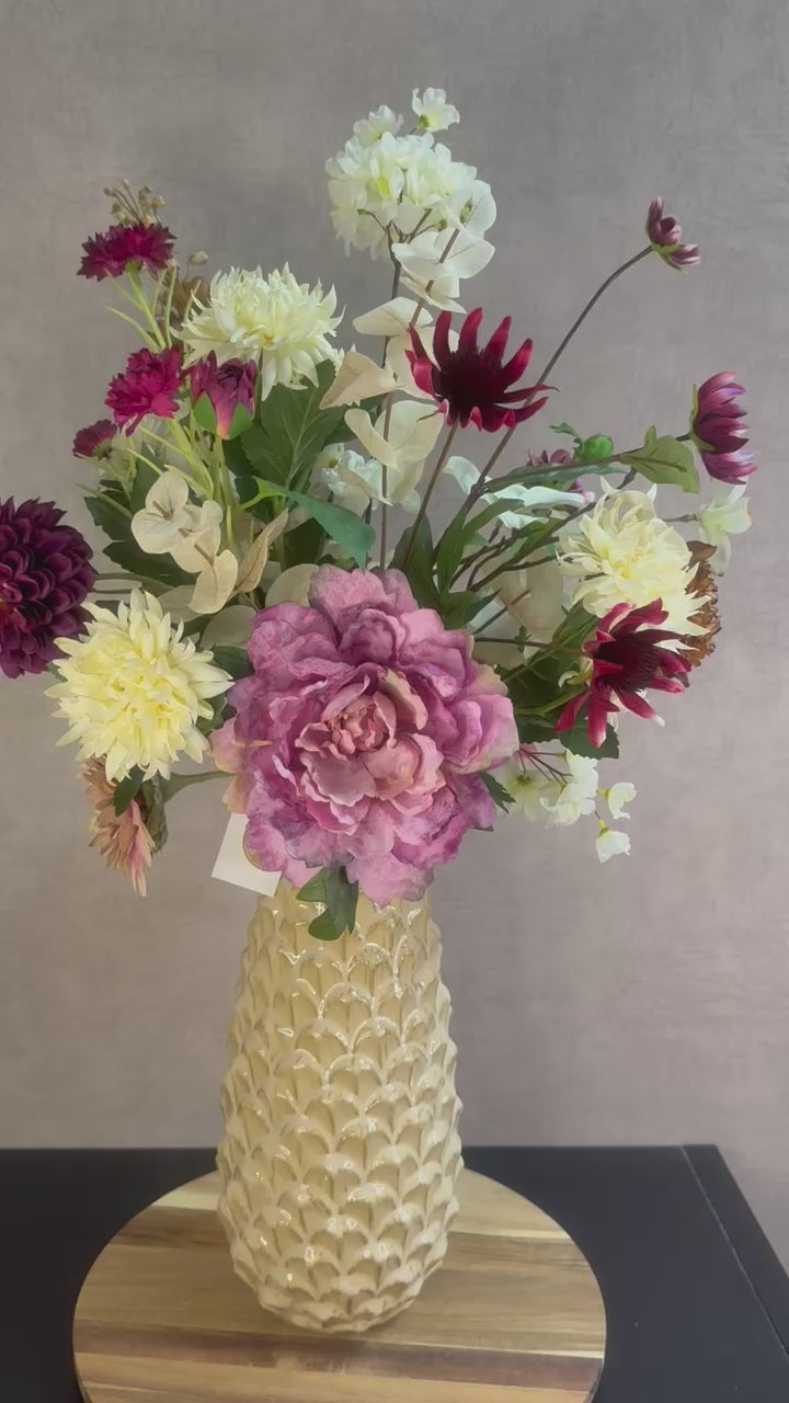 Video van Kunstboeket Noëlle – volle bos kunstbloemen in beige, bruin en bordeaux tinten in een beige vaas tegen grijze achtergrond.