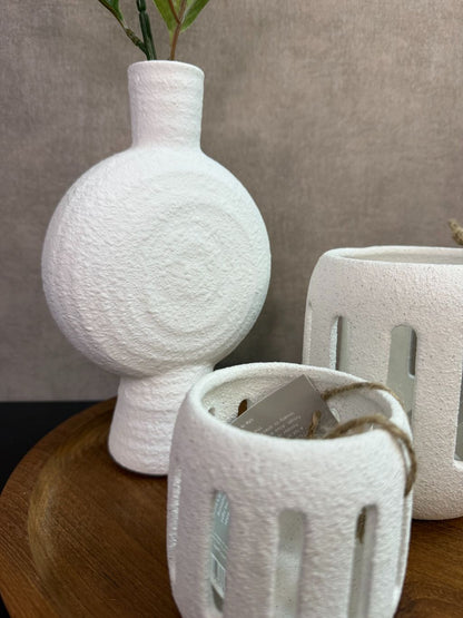 Tafel decoratie set met houten dienblad, witte vaas met bloem en twee witte waxinelichthouders tegen een neutrale achtergrond.