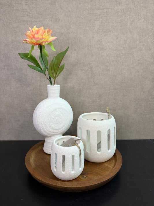 Tafel decoratie set met houten dienblad, witte vaas met bloem en twee witte waxinelichthouders tegen een neutrale achtergrond.