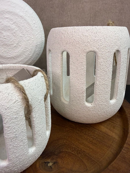 Tafel decoratie set met houten dienblad, witte vaas met bloem en twee witte waxinelichthouders tegen een neutrale achtergrond.